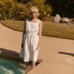 Selma Blair Instagram - So many places to be alone, so many escapes. So many summers that we can keep—if we want to—for ourselves, keep forever. And we had better. - Joan Didion, American Summer. 📸 @raulromo [Image Description: A series of photographs of Selma, with short blonde hair in a white dress in and around a pool with her dog Scout. She is using her blue cane from @neowalksticks.]