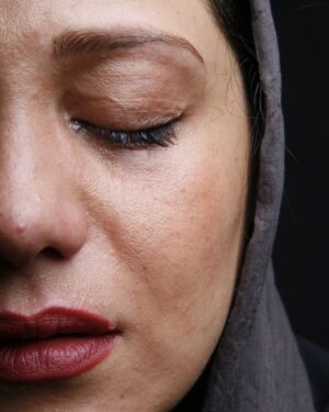 Shabnam Moghadami Instagram - .
صورتم از سوختگی ِ هُرم ِ آفتاب و شرجی درد می کرد و دست هام از الکل زدگی ِ کابوس ِ کرونا پلاسیده بود. پاهام جان ِ کشیدن ِ تن ِ خسته و صبور ِ چهارده پانزده ساعت توی گرما کار کرده ام را نداشت .خنده ام را اما نمی گذاشتم گُم شود.زندگی همین است دیگر !نباید به بهانه ی سختی های گذرا ،تلخش کنیم به کام ِ خود ‌و به کام ِدیگران.( این را با خودم مثل ِ ذکر ِ شُکر ،همواره تکرار می کنم).
شب که می آید،تب آلود و خسته جان، زندگی را بی حتی وقفه ای کوتاه در خواب هایم ادامه می دهم ، مثل ِ همیشه. 
خواب ِ پدرم را می بینم، جایی سبز و بارانی هستیم مثل ِ جنگلی آشنا و صدای فرهاد می پیچد در خوابم. برای بابا چای ریختم و حتی بخار ِ چای رایادم هست که تا کجای لیوان بالا می آمد.
بابا گفت زمستان ِ اخوان را برایم بخوان. خواندم. صدایم می رفت توی آواز ِ فرهاد.دست می کشید روی علف های خیس. گفتم نکن ! آستینت تَر شد از شبنم ...گفت امتحان کن...خستگی دست هایت در می رود...دست کشیدم روی سبزه ها ...
و نفهمیدم چی شد که یکباره گفت : نسل ِ عجیبی ست نسل ِ تو... بی درد و رگ نه اما پوست کُلفتید!
گفتم : نسل ِ تو چی؟...و نسل ِ پیش از تو؟ برایم بگو از تفاوت های مان.
سکوت کرد. چای نوشید. جنگل و مه را تماشا کرد و به فرهاد گوش داد .پاسخی نبود.پاسخی نداشت.
و دیگر روی علف های خیس دست نکشید.
و من از این خواب ، از این سکوت، از این سکون بیدار نمی شدم.یک جایی صدای ِ گریه می آمد.
.
عکس را پیام ایرایی سال ها پیش برداشته از من. راستش دلیل ِ غصه و گریه ام خاطرم نیست.به نظرم اما عکس ویژه ایست.
بی روتوش و اصلاح رنگ، طبیعی و عین ِ زندگی ست.