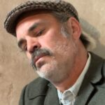 Steven Ogg Instagram – A joyous call to action for us all
with bittersweet humanity
with the power of friendship 
with the power of creativity 
all healing us in unexpected ways.

“Where did life go? Every day I find myself asking this one same question of the mirror, yet the answer always eludes me. All I see is a stranger staring back…pain nags at my neck and I marvel at the minor miracle that my body has held out this long. Sometimes it feels as if it is held together by little other than strings of memories and sinews of hope. The mind is a museum coated in dust.

But I was a young man once, so young and green, and that can never change. Memory allows me to be so again. 

I knew not what language could do then. I did not yet understand the power and potency of words. The complex magic of language was as alien as the altered country that I saw around me during that summer…

The whole place needs a lot of work but I am too ancient for all that now…the old word processor still functions though. There’s power in the both of us, there is electricity, and while it is still there I have something to share.

Sitting here now by the open window, a glissando of birdsong on the very lightest of breezes that carries with it the cent of a final incoming summer, I cling to poetry as I cling to life.” @benmyers76 #theoffing #novel #inspiration @element_pictures @catalystglobalmedia