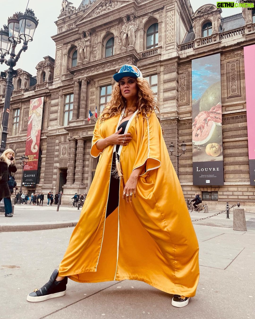 Tyra Banks Instagram - As a teenager, I walked the streets of Paris, going from casting to casting, hoping to get chosen. Cut to decades later… Moments after the @louisvuitton x @kidsuper men’s fashion show, and I have no shame in getting my pose on in front of the @museelouvre rocking a Louis cap Colm gave me and a golden kaftan I picked up from an Abu Dhabi desert hotel gift shop. Every #Paris street is a photo studio. Remember that. 💪🏽🇫🇷📸