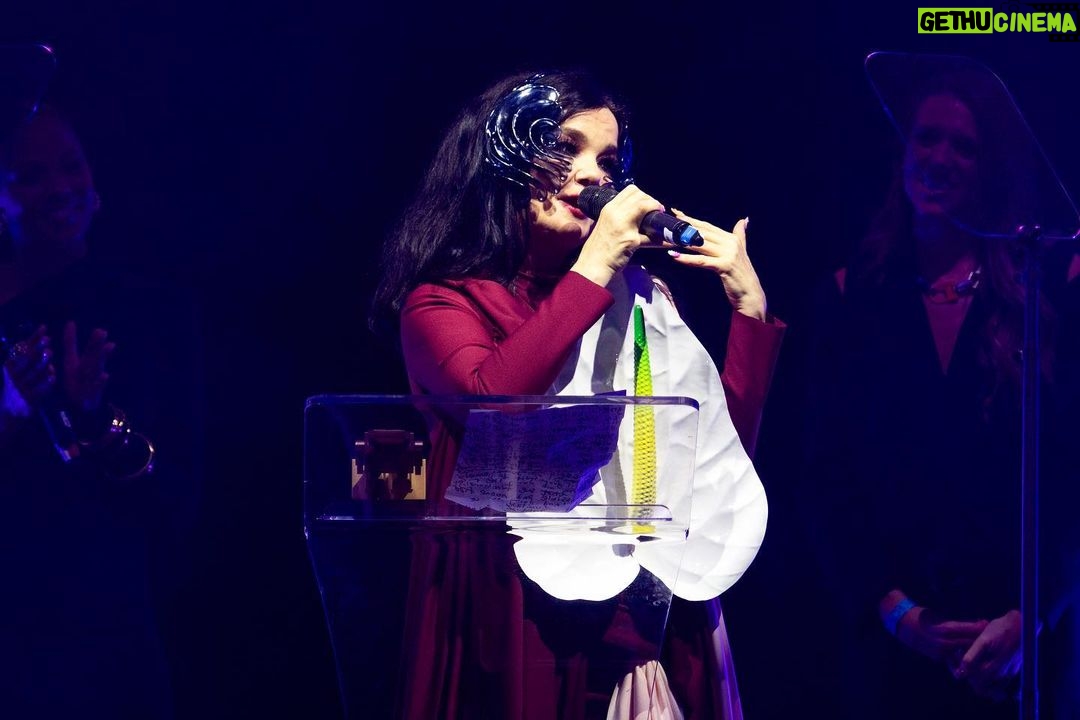 Björk Instagram - so proud to receive this award !! i would like to thank OLI ( one little independent ) who have taken care of me since i was a teenager. so touched to be amongst them UK indies ....... i would like to thank my cornucopia production live crew once again : derek birkett , peter van der velde , bergur þórisson , david levy , john gale , bruno poet , tobias gremmler , lucrecia martel , chiara stephensson , richard white , james merry , edda guðmundsdóttir , rosamari llagostera , heimir sverrison , margrét bjarnadóttir , isshehungry , andrew gallimore , steve jones , santiago felipe thank you @onelittleindierecords @aim_uk bjork dress @richardmalone anthurium flower @loewe mask @james.t.merry makeup @andrewgallimakeup hair @danieldyer72 manicure @suki_nailz styling @eddagud photos @santiagraphy Roundhouse