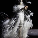 Björk Instagram – @coachella 

conductor @bjarnifrimann 
orchestra : hollywood string ensemble
björk dress @noirkeininomiya 
headpiece @james.t.merry 
bodysuit @solangel 
makeup @isshehungry 
bjarni frímann top @maisonvalentino 
skirt @weishengparis 
styling @eddagud 
photos @santiagraphy 
drone photos @charles.reagan 
mask production @secca_kanazawa 
3D printing support by DMM.make
mask technical direction @suganokaoru 
producer : reiko kunieda.

drone light performance by
@studio.drift 
@dronestories.show 
@twofiftyk 
@novaskystories 
björk creative direction :
björk , @james.t.merry