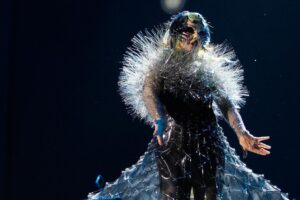 Björk Instagram - thank you @coachella for a wonderful evening !! 
 
conductor @bjarnifrimann 
orchestra : hollywood string ensemble 
björk dresses @noirkeininomiya
headpiece @james.t.merry
latex slip dresses @xvenusprototypex
bodysuit @solangel 
hairpiece @tomikono_wig
makeup @isshehungry
bjarni frimann wearing @jonnycotastudio
styling @eddagud
mask design & 3D sculpt @james.t.merry
mask production @secca_kanazawa
3D printing support by DMM.make
mask technical direction @suganokaoru
producer : reiko kunieda
photos @santiagraphy
