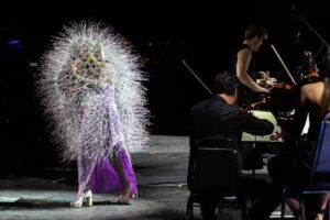 Björk Instagram - thank you @coachella for a wonderful evening !! 
 
conductor @bjarnifrimann 
orchestra : hollywood string ensemble 
björk dresses @noirkeininomiya
headpiece @james.t.merry
latex slip dresses @xvenusprototypex
bodysuit @solangel 
hairpiece @tomikono_wig
makeup @isshehungry
bjarni frimann wearing @jonnycotastudio
styling @eddagud
mask design & 3D sculpt @james.t.merry
mask production @secca_kanazawa
3D printing support by DMM.make
mask technical direction @suganokaoru
producer : reiko kunieda
photos @santiagraphy