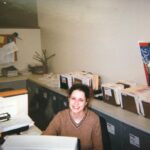 Jenna Fischer Instagram - #OneDayMay Today’s Prompt…Throwback version of me… Here I am working one of my many admin jobs in my years before landing on The Office. Please admire the elaborate filing system behind me. I was very proud of that. I liked this job. I worked as an assistant to a media buyer. It was mostly data entry (and filing). The Dodgers pennant belonged to the assistant before me. The daisies are mine!