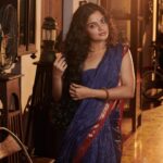 Nikhila Vimal Instagram - Brocade of Mau (historically can have visual similarities with cotton Paithan and venkatgiri cottons too) A revival Mau cotton range of saris with the quintessential 3 cm’s old school ‘chataai’ border consists of uninterrupted gold pattern of diamonds placed in the margins with rows of gold triangles and fine parallel cotton stripes along the edges. The cross border frames a Pallav with two Star Konias. The field of the sari has checks in gold zari over an old indigo ground Muse @nikhilavimalofficial seen draping a Mau cotton revival sari. Featuring- @nikhilavimalofficial Photography - @shafishakkeer HMUA - @rizwan_themakeupboy Styling - @arjun_vasudevs Jewellery - @tanishqjewellery Matancherry