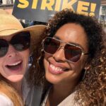 Sarah Rafferty Instagram - Reunited with my @iamginatorres on the picket line. There was a lot of kissing. And I will keep meeting her and kissing her on the picket line until we get a fair deal for all our @sagaftra (and @wgaeast @wgawest) brothers and sisters. Even though I chose to post the lighthearted bits…make no mistake, this is a fight for the dignity and future of our industry, the right to make a decent wage that is commensurate with our value to the business, the right to participate in the success of our work (I’m looking at you streamers who buy out our residuals and exclusively hold us for YEARS between seasons), the right to care for our families by earning enough to have health coverage (again with the erasure of residuals and ever shorter seasons and longer contractual holds keeping us hostage without the freedom to seek other work), and the right to create a path forward for future generations (how ‘bout when actors are “relocated”, even tho you know we can’t relocate full time to Canada for example, we simply receive adequate financial support in temporarily moving our lives abroad, and reasonable guard rails against a future where our work and likeness is fed to AI and used without consent and compensation). Our solidarity is stronger than their corporate greed. #unionstrong #sagaftra