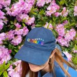 Bonnie Wright Instagram - Say hello to Go Gently’s pride EARTHLING organic cotton baseball cap 🌈🧢 We made this special cap for our documentary TV show hosted by @thisisbwright and @pattiegonia The show is all about celebrating the beautiful spectrum of identities of the folks working to address the climate crisis. The caps are now available for everyone to enjoy as they celebrate love and equality this summer!
$5 from each hat sold will be donated to @bravetrails, a non-profit organization with the mission of connecting LGBTQ  youth to their people, place, and passion. They offer leadership summer camps in California & Maryland, family camps, backpacking, mental health services, and year-round leadership programming. You can learn more about Brave Trails at www.bravetrails.org or by following them @bravetrails
🧢The base colour is navy blue and is made from organic cotton with an adjustable strap for size. Each letter and star represent the colors of the current pride flag. Happy Pride Earthlings 🌈
