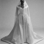 Vivienne Westwood Instagram - Our Nova Bagatelle gown features a design that echoes the iconic blindfolded bride from the Spring-Summer 1997 show, for the 'Vive La Bagatelle' collection. The gown creates a regal silhouette with a cinched waist and a romantic, off-the-shoulder draped neckline. The full skirt features deep pleats and a long almond shaped train. ⁠
⁠
This season the Nova Bagatelle is offered in a double duchesse fabric, styled here with the Ballerina length tulle veil. ⁠
⁠
Photography by @kingsley_ifill⁠
Styling by @florahuddart⁠
⁠
#VWBridal #WestwoodBridal