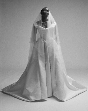 Vivienne Westwood Instagram - Our Nova Bagatelle gown features a design that echoes the iconic blindfolded bride from the Spring-Summer 1997 show, for the 'Vive La Bagatelle' collection. The gown creates a regal silhouette with a cinched waist and a romantic, off-the-shoulder draped neckline. The full skirt features deep pleats and a long almond shaped train. ⁠
⁠
This season the Nova Bagatelle is offered in a double duchesse fabric, styled here with the Ballerina length tulle veil. ⁠
⁠
Photography by @kingsley_ifill⁠
Styling by @florahuddart⁠
⁠
#VWBridal #WestwoodBridal