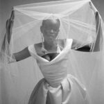 Vivienne Westwood Instagram - Our Nova Bagatelle gown features a design that echoes the iconic blindfolded bride from the Spring-Summer 1997 show, for the 'Vive La Bagatelle' collection. The gown creates a regal silhouette with a cinched waist and a romantic, off-the-shoulder draped neckline. The full skirt features deep pleats and a long almond shaped train. ⁠
⁠
This season the Nova Bagatelle is offered in a double duchesse fabric, styled here with the Ballerina length tulle veil. ⁠
⁠
Photography by @kingsley_ifill⁠
Styling by @florahuddart⁠
⁠
#VWBridal #WestwoodBridal