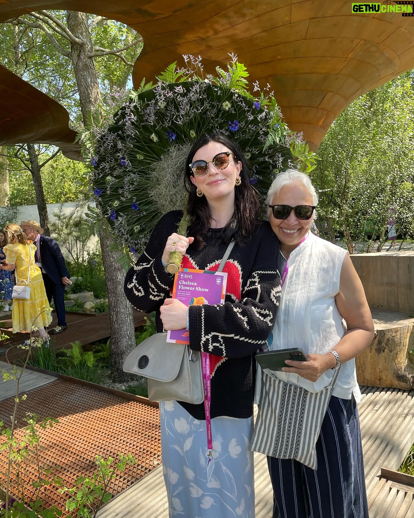Aisling Bea Instagram - Avoided drawing attention to myself today @the_rhs Chelsea Flower show, if you zoom in, you will be able to make me out. I LOVE power plants & BIG bushes & there were so many on display today. But my favourite garden was my friend @tommasseyuk ‘s one for @wateraid which he co-designed with Je @studioweave - both seen here with @josh_widdicombe who did not get the “dress like a flower”memo. The garden features flowers and plants which are resilient to extremes in weather, especially rainfall, which is more important than ever with our changing climate. Also some flowers which may be not deemed as fancy and pretty as others, which breaks my hear as they are ALL loveable. Almost one in ten people around the world don’t have access to clean water close to home, and the climate crisis is making it worse. So the mushroom like design is a rainwater-harvesting pavilion inspired by WaterAid’s work in communities around the world. “But tell us about your outfit so we too can completely cover up in the sun!” Well, I tried to wear an eco outfit today featuring a gorgeous but ill advised in the sun jumper from small brand @theslowlove , a flowery dress from @reformation who make their clothes from leftover material, jewellery & a handbag which fits everything from a variety of charity shops & some earth day shoes from eco brand @vivaia_official who make their shoes from recycled materials and try to reduce waste in their factories. Bought everything so you can TRUST ME. Thanks to @thenewtinsomerset & @the_ivy_collection for feeding myself, my brother in law @mkidao & auntie in law - we are stuffed and covered in pollen. And thank you to @lordham for making sure my hair was nice and shiny. xxx