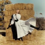 Amber Valletta Instagram - “When I returned to modelling in my 40s, I did so with an entirely different perspective on fashion,” writes @AmberValletta in the January 2024 issue of #BritishVogue. “We’ve got to shift our mindset about the environment from one of fear to joy and love, of sacrifice and enjoyment. It’s a relief to consume less, to no longer be burdened by possessions you never needed in the first place.” Click the link in bio to read the interview, and see the full story in the new issue, on newsstands Tuesday 19 December. #AmberValletta photographed by @CharlotteMWales and styled by @PoppyKain, with hair by #ShingoShibata, make-up by #KanakoTakase, nails by @TrishLomax, set design by @MaxBellhouse, movement director by @EricVonChristison and production by @FaragoProjects. [Image one shows Amber Valletta, a white woman, from the waist up. She is standing in a sun-dappled forest, her left hand in the pocket of her black double-breasted jacket, while her right hand is raised in front of her face as if to shade it from the winter light. The deliberately frayed cuffs of a white striped shirt peek out at the ends of her coat sleeves. She has gold and pearl earrings in her ears, with a detached shirt collar styled jauntily around her neck. Image two shows a full-length portrait of Amber Valletta, a white woman, standing in front of a haystack in an English country field. With her left leg, she kicks some dried grass into the air, her knee-length black boot visible beneath the hem of her long-sleeved prairie-style white dress, which is cinched at the waist with a wide black leather belt. Image three Amber Valletta, a white woman with blonde hair and blue eyes, leaning her head on her arms, which are resting on the back of a piebald horse. She wears a rough brown jacket, and her left arm is extended out towards the camera. Trees and a wintry sky are visible in the background.]