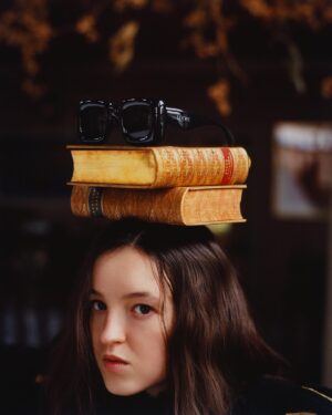 Bella Ramsey Instagram - Books are supposed to go on heads and Bella’s are supposed to go on postboxes and glasses are supposed to go on books on heads and then there’s a tortoise. Thank you Vanity Fair and friends. 🐢🙆🏻🎩📚🕶️