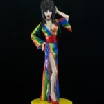 Cassandra Peterson Instagram – ANNOUNCEMENT! 🏳️‍🌈 🖤
➖
Elvira – Over the Rainbow Elvira 8” Clothed Figure 
➖
Celebrate Pride Month with Elvira, Mistress of the Dark! The devilishly delightful Cassandra Peterson has played the part of Elvira for more than 40 years with grace, humor and more than a little camp. NECA is proud to present this “Over the Rainbow” Elvira figure, celebrating the horror and queer icon in a never-before-seen, sparkling rainbow dress for your collection. With an original tailored fabric gown, glittery ruby red heels, and a yellow brick display base, she’s definitely not in Kansas anymore! This fully articulated 8-inch action figure features new faceplate technology with two interchangeable expressions and hands, including brand new ones that allow you to recreate Elvira’s signature pose! She comes with a book accessory of Peterson’s memoir, “Yours Cruelly, Elvira”, and a double-sided flag with 10 stickers to customize and show your unique pride! 
➖
Available now on thenecastore.com, and shipping to your favorite NECA retailer in June!
➖
#Elvira #MistressoftheDark #Pride #OvertheRainbow #CassandraPeterson #NECA  #actionfigure