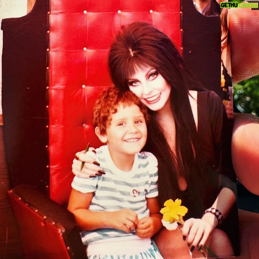 Cassandra Peterson Instagram - Check out this cute #flashback pic shared by @disneydebauchery 🖤 “I first fell in love with Elvira when I was super little, I use to watch the TV show religiously. This was before she did all the movies and stuff. One day my mom told me that she had a surprise for me, but she wanted to take me out and get my haircut first. I got the worst hair cut I have ever had in my life that day, even my Mom was upset. The surprise was Elvira was doing an Easter Bunny/Santa Claus style photo opportunity in our local grocery store parking lot and now I had to go see her with a stupid hair. I stood in that line and felt so embarrassed I almost cried but I was determined to meet her. All the people in line were horny teenaged boys so she was probably thrilled that this young nervous little girl was so excited to see her with flowers she clearly picked out of the flowerbeds in the parking lot. She was so fantastically sweet and amazing. I’ll never forget it.” #elviramistressofthedark #elvira #younggothgirlinthemaking #flashbackfriday