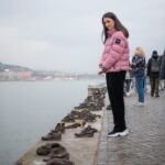 Chris Flores Instagram - Continuação posto anterior… Às margens do rio Danúbio, a poucos passos do Prédio do Parlamento Húngaro, está o emocionante monumento que homenageia os judeus húngaros mortos por membros da milícia da Cruz Flechada, um partido que compartilhava as mesmas ideias do partido nazista de Hitler. Entre os anos de 1944 e 1945, Ferenc Szálasi, aliado dos nazi alemães, governou a Hungria e foi o responsável direto pelo assassinato coletivo de aproximadamente 15 mil judeus, além de enviar 80 000 pessoas, incluindo muitas mulheres, crianças e idosos, da Hungria para a morte no campo de concentração de Auschwitz. Após a guerra, Szálasi e outros líderes da Cruz Flechada foram julgados como criminosos de guerra pelos tribunais soviéticos. Adultos e crianças eram executados em Budapeste às margens do rio Danúbio. Antes de serem alvejadas e levadas pela correnteza, eram obrigados a ficar enfileirados e a retirar os sapatos, bens de valor à época. O Memorial Sapatos às Margens do Danúbio é uma homenagem do cineasta Can Togay, produzido pelo escultor Gyula Pauer, aqueles que sofreram durante o período nazista na capital. A obra, feita em 2005, mostra cerca de 60 pares de sapatos de ferro, de homens e mulheres, modelados ao estilo da década de 40. Alguns visitantes, sensibilizados, deixam flores e recados dentro dos sapatos. Continua no próximo post… 📷 @ricorreafoto