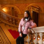 Chris Flores Instagram - Continuação post anterior… As escadas bifurcadas de mármore do hall de entrada da Ópera conduzem à grande escadaria, onde a experiência estética se torna ainda maior. Os dois lances de escada conduzem às entradas do térreo do auditório. Pinturas de Mór Than adornam os nove retângulos dos caixotões dourados que embelezam o teto espelhado acima da escadaria principal. Os tópicos destes são o Despertar da Música e o Poder da Música. Os retângulos alongados nas laterais representam a cena principal da disputa entre Apolo (tocando lira) e Mársias (tocando flauta), intitulada O Julgamento de Tholos. De acordo com a história mitológica, o deus do rio Tolos decidiu que Apolo vencera a disputa, e o sátiro pagou por sua insolência sendo esfolado. A pintura ao redor do lustre faz referências a Hera, Hades, Zeus e Poseidon. A lesene que corre ao longo da parede retrata três cenas ligadas a Orfeu: as pinturas de Mór Than mostram-no primeiro em frente à porta de entrada para o submundo, depois trazendo Eurídice do submundo e, finalmente, ilustram a sua morte. Representações alegóricas de Belas Artes e Arquitetura estão localizadas acima da entrada do Bar Feszty, sendo que este último contém os planos da Ópera. Continua no próximo post… 📷 @ricorreafoto