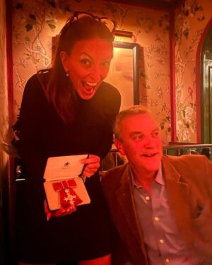 Davina McCall Instagram - This looks like I’m harassing a diner at the restaurant 😂😂😂 but I was harassing my besties hubby , nothing new there … been doing it for decades 😂😂😂😂…. I can’t think of a better way to celebrate than with them @mdlondon 🥳😍🥰 and our families … but Tilly and Bache you were really really missed … really really . But with us in spirit . What a day x thank you for all your messages . Congrats to all the other wonderful recipients we met today and all the wonderful people at Buckingham Palace who made it so special . Also @broadwicksoho for fantastic food and my flowers 🧡🩷💝 wow x going to sleep with a massive smile on my face . Btw @abigailrosewhite found me my wonderful dress by @rebeccavallance and fascinator by @camillarosemillinery and shoes by @ginashoesofficial
