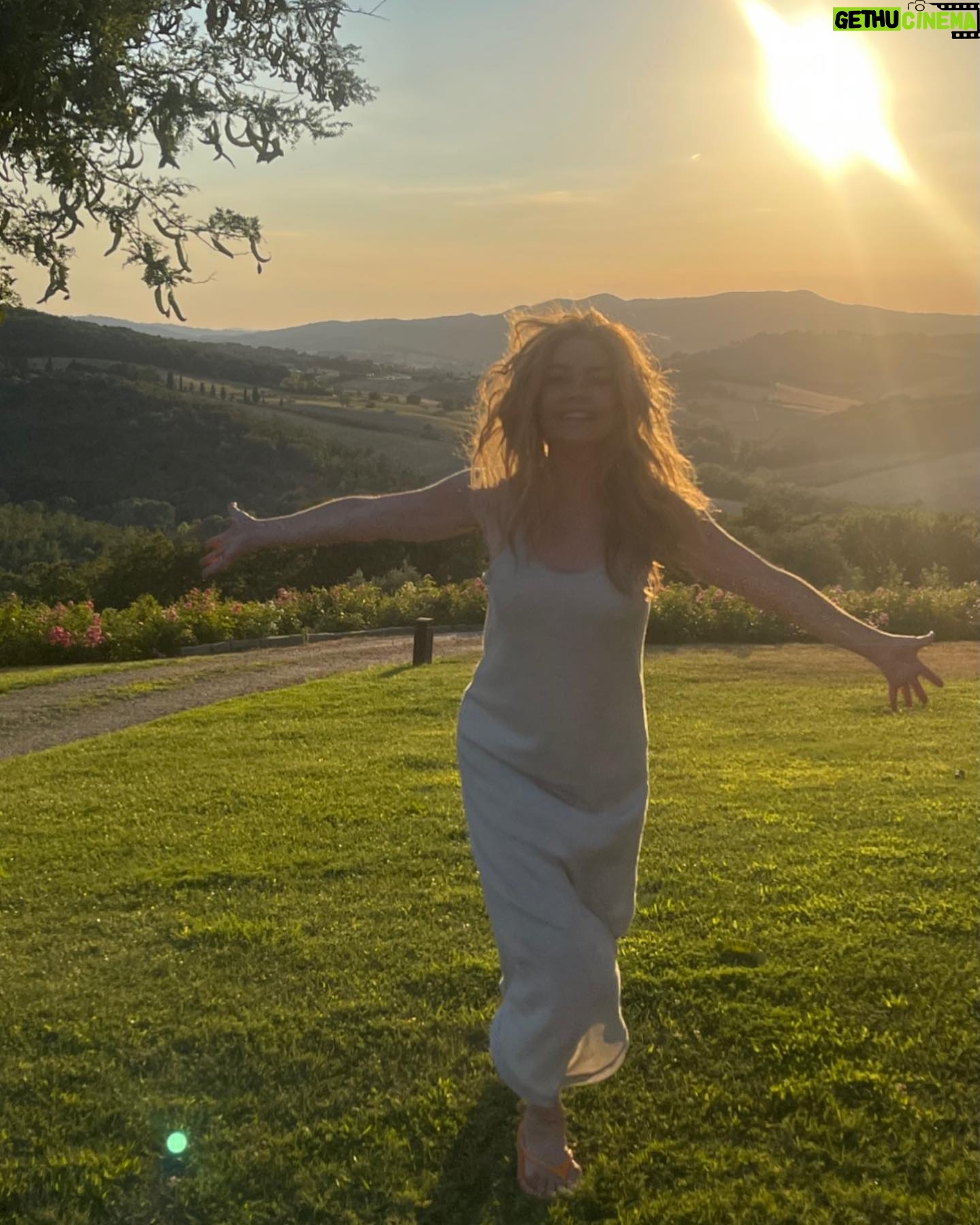 Denise Richards Instagram - It’s been a dream of mine & my husband’s to go to Tuscany. I was so lucky to shoot in Italy this past week so we decided to make a big trip out of it. Here we are Trying to capture the best pic & me looking ridiculous and my hair all crazy( we just went to the spa) I look at some of your photos and wonder who the hell is there to take them? Do you all travel with someone? Do you ask someone close by to shoot it? I’m so curious 😂 because most of you all that I follow your vacay pics looks really good!