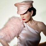 Dita Von Teese Instagram – English translation of 
‘FEMME DE TÊTE’:
Assertive woman.

Soft but unyielding, this satin officers cap was inspired from @ditavonteese ‘s fetish modeling days, with a candy colored twist. (Obviously available in Black as well, we haven’t gone completely mad.) 

@ditavonteese by @travis_shinn 
Dresses:
@maguydechadirac 
@lenahoschek 
@jennypackham 
Jewlery:
@sillamjewelry 

#hoodxdita #travisshinn #ditavonteese #hoodlondon #millinery #vintagestyle #glamour