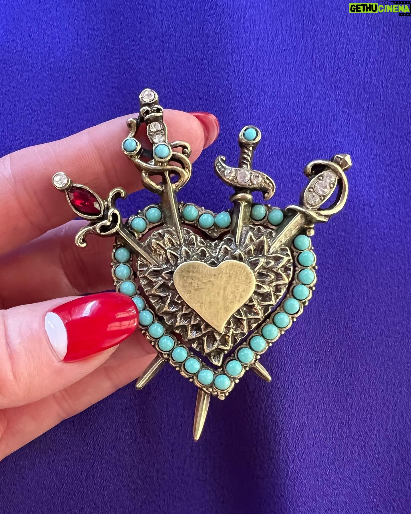 Dita Von Teese Instagram - The Valiant Heart Brooch To know love is to know its sweeps of passion and pain, and of the self-knowledge and resilience each one of us can find strength in, as robust as a well-crafted sword. Four swords brace the heart, the universal symbol of love and joy, in this hand-sculpted #brooch, finished in bronze and based on a vintage #1940s era treasure from my collection. It is a favorite because of its romantically regal effect, evoking #heraldic insignia. Take heart, valiant ones! This is a badge not about the end, but rebirth. A meaningful gift—yes, even for yourself. Swarovski crystal elements accent the swords and heart outline in diamanté and garnet, as well as turquoise beads. The center heart is suitable for engraving initials or a message. Made in the USA 🇺🇸 Exclusively at luxfaire.com