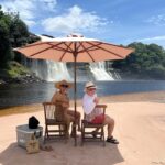 Dora Mazzone Instagram - Cada vez que te conozco más me enamoro más de ti… 🇻🇪 Me perdonan el spam pero tengo tanto material que se me va a pasar de moda en la galería de fotos 🌿🐒🌴🦜🐸 #canaima 1. El Salto El Hacha frente a la Isla Anatoly (se forma una playita en sequía de lo más rica y privadita… malo?) 2. Vista al Salto desde la curiara.. (el agua es color Pepsi y no hay ni caimanes ni pirañas pero si corrientes fuertes…) 3. Ella es una princesa indígena.. habla español y pemón y tiene el cabello más brillante que he visto.. pocas veces usa shampoo, se lava el cabello en la laguna. 4. Yo posando.. viviría aquí! #kanaimö 5. Cuál #maniñayerichana en #kanaimö 🌿 6. Con mi gordo que no me lo quita nadie diría @mimilazod .. y en la cava mi Polar Pilsen 🍻 7. Metiendo la barriga para la foto! Mi falda es de @dibronze.ve 8. A lo lejos los majestuosos Tepuyes ⛰️ 9. En una de las cabañas de @wakawena uffffff al natural y orgánica! 10.Con mi amigo Rodrigo… estaba antes en @aramerulodge y me tomò fotos! Habla pemón y español Vengan a conocer este paraíso! Venir a @wakawena es del más allá!! #doramazzone #venezuela 🇻🇪🦜