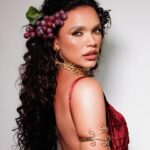 Giovana Cordeiro Instagram - O teatro começou com procissões para cultuar a colheita da uva, regado de muito vinho e manifestações artísticas. Isso me lembra muito o que a @gresuportodapedra faz hoje no seu primeiro ensaio na Sapucaí: um cortejo com suas alegorias, o seu despudor físico e sua alegria popular, sempre com intuito de compartilhar a sabedoria. Assim nasceu o meu ofício, assim nasceu o ofício de @brincantenobrega. Nesse momento, a Porto da Pedra homenageia Lunário Perpétuo, um almanaque que guiou a vida de muitos nordestinos por dois séculos e que foi representado pela @ciaosbrincantes no teatro! A minha fantasia de hoje homenageia todos os artistas que atravessam gerações com compromisso de informar e conscientizar seu povo. Estou aqui em nome dos meus, em nome dessa comunidade que faz questão de contar essa história com todo seu amor e sua gana. A arte é do povo e para o povo! Viva a arte! Viva o teatro! Viva Baco e Dionísio! Viva Antônio Nóbrega! Viva o Nordeste e o povo brasileiro! Que a arte sempre tenha espaço para se manifestar com liberdade, alegria e compromisso. EVOÉ! 🍇🎭 Beleza: @danibstudio Look: @ateliermarcioferreira Sandálias: @viferracooficial