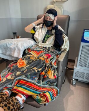 Grace Helbig Instagram - Scenes from chemo round 5! We’re officially 5/6th of the way through chemo!!! I can’t even process that right now, it’s all been so surreal. I brought this hat gifted to me by a friend of @mametown’s for a lil photo shoot. (If you listen to TMGW you know!) @elliottmorgan thought it was maybe “too dark” of a joke. Maybe he’s right, but I’ve lost my baseline for what’s normal or appropriate or “real life” at the moment so we’re just having fun! 5 infusions down! The adorable horrors of recovery await but we’re fucking doing it! 💪🏻🙃 #aintdeadyet