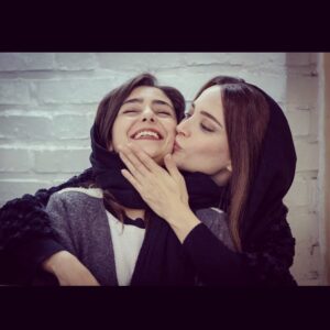 Hasti Mahdavifar Instagram - خب سلام. یه مجموعه عکس از ماجرای نیمروز-رد خون همراه با توضيحات :
.
عکس اول : صحنه آمادس .کارگردان خواب هستن،با سر دردی شدید. منم با اخم منتظر بیدار شدن ایشان.
.
عکس دوم : بهنوش جانم (معروف به مامی) در حال گرفتن ماچی شدید از بنده
.
عکس سوم:کارگردان زمانی که نمیخواد هیچ حرفی رو بشنوه!
.
عکس چهارم: مذاکرات من و گارکردان و تلاش من برای به کُرسی نشوندن حرف خودم و ابراهیم امینی (نویسنده ) در هاله ای از ابهام که پیش خودش داره میگه پس من اینجا چی کاره ام!
.
عکس پنجم: اها این عکس . یه عکس آنالوگ که مجید طالبی گرفته ، من نشسته در صحرا،همراه با غروب،با پایی سبز و فکر کردن به فرق بین پا داشتن و نداشتن!
.
عکس ششم: تقریبا جمعی از سر گروه ها زمانی که هنوز رو فُرم و سرِ پا بودن.
.
عکس هفتم : اهااا اینم خیلی نکته داره، گروه کارگردانی همراه با گروه صدا تصویر.
 اما نکته: اون کتِ قرمزی که تن منه بعد گرفتن این سکانس ناگهان غیب شد. ینی در واقع پیچونده شد.ینی در حقیقت دزدیده شد. حالا من اسم نمیبرم توسط کی...
.
عکس هشتم :کارگردان مشغول خاراندن پایش، و عکاس مشغول خوابی عمیق.
.
عکس نهم : من در حال غش غش خندیدن، یادم نیست به چی ! اما برام چیز طبیعی ای بود این خنده های از ته دل سر این کار. کلا کارم فقط خندیدن بود اونجا. ینی ناخواسته از همه ی حرکات و سکنات و حرفای دوستان خنده ام میگرفت.
.
عکس دهم : خب ،این عکس سه تا عکسه . از بالا سمت چپ : اختلاف بین کارگردان و دستیارش امیرحسین.
از بالا سمت راست : تفاهم بین کارگردان و دستیارش.
عکس پایین : تکرار دائم اختلاف و تفاهم در طول فیلمبرداری بین کارگردان و دستیارش امیر حسین.
نظر من راجع به عکس آخر : بیشتر داره میگه : از کجا اومدی ؟ 
ازین ور اومدیم.
کجا داری میری؟ 
نمیدونم بریم ببینیم چی میشه دیگه...
.
پ.ن اول : بقیه عکسا با توضیحاتشون رو میذارم استوری (اینجا دیگه جا نداشت)
.
پ.ن دوم : بخشی از این عکسها رو مجید طالبی گرفته ، بخشی رو من، و بخشی ناصر میرخانی