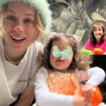Iliza Shlesinger Instagram - We are Jewish but Sierra’s LA Grandma isn’t which means she gets Easter (and an Easter basket! I’m so jealous 🤍) and we all get Christmas. We filled eggs with Easter “candy” like… raisins and cashews and dried peaches and she had the best time. We did the neighborhood egg hunt too but she didn’t eat the chocolate because Mommy, who never lies, told her it was too spicy. Highlight for me was her holding this little blue bunny so delicately like it was a baby. Nothing will beat last year’s Easter outfit (last slide) but this one came close. 🐣🐰