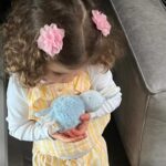 Iliza Shlesinger Instagram - We are Jewish but Sierra’s LA Grandma isn’t which means she gets Easter (and an Easter basket! I’m so jealous 🤍) and we all get Christmas. We filled eggs with Easter “candy” like… raisins and cashews and dried peaches and she had the best time. We did the neighborhood egg hunt too but she didn’t eat the chocolate because Mommy, who never lies, told her it was too spicy. Highlight for me was her holding this little blue bunny so delicately like it was a baby. Nothing will beat last year’s Easter outfit (last slide) but this one came close. 🐣🐰