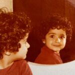 Kamand Amirsoleimani Instagram - از بچگی لبخند میزدم. از اون موقع آینه پیش روم بوده تا خود واقعیمو ببینم و از همه چیز مهمتر جشمامه که خودم میفهمم چقدر مهر و عشق درونش جاریه. خوشحالم که الان،امروز هم بخوام عکس بگیرم همین ژستو میگیرم خوشحالم که سختیها و مشکلات و فشار زندگیم مهر و لبخند رو ازم نگرفته. و کیف میکنم از اینکه هنوز خودمو تو آینه میبینم و با خودم صادق و روراست و بی پرده حرف میزنم. امروز برید سراغ آلبومتون و خودتون در کودکی رو بهتر ببینید و بشناسید. سال جدید سال شماست🌹