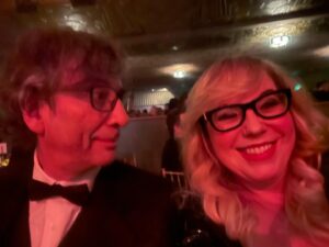 Kirsten Vangsness Instagram - My arm candy (not really, I find our friendship very nutritious, he’s more like arm mushrooms and I was his guest so that makes me the mushrooms) @neilhimself was wearing THE COOLEST SUIT while being his lovely self and being honored for being THE COOLEST CREATIVE  @theartofelysium Neil Gaiman’s Heaven twas true nerd heaven- the set was a library and people read from books and genius @jeremyoharris was our librarian for the evening. @theartofelysium is doing extraordinary things using the arts to create heart opening experiences for folks in our most vulnerable communities, it’s a lovely place to volunteer and give to and I was happy to learn of them this evening.