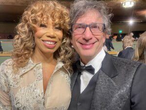 Kirsten Vangsness Instagram - My arm candy (not really, I find our friendship very nutritious, he’s more like arm mushrooms and I was his guest so that makes me the mushrooms) @neilhimself was wearing THE COOLEST SUIT while being his lovely self and being honored for being THE COOLEST CREATIVE  @theartofelysium Neil Gaiman’s Heaven twas true nerd heaven- the set was a library and people read from books and genius @jeremyoharris was our librarian for the evening. @theartofelysium is doing extraordinary things using the arts to create heart opening experiences for folks in our most vulnerable communities, it’s a lovely place to volunteer and give to and I was happy to learn of them this evening.