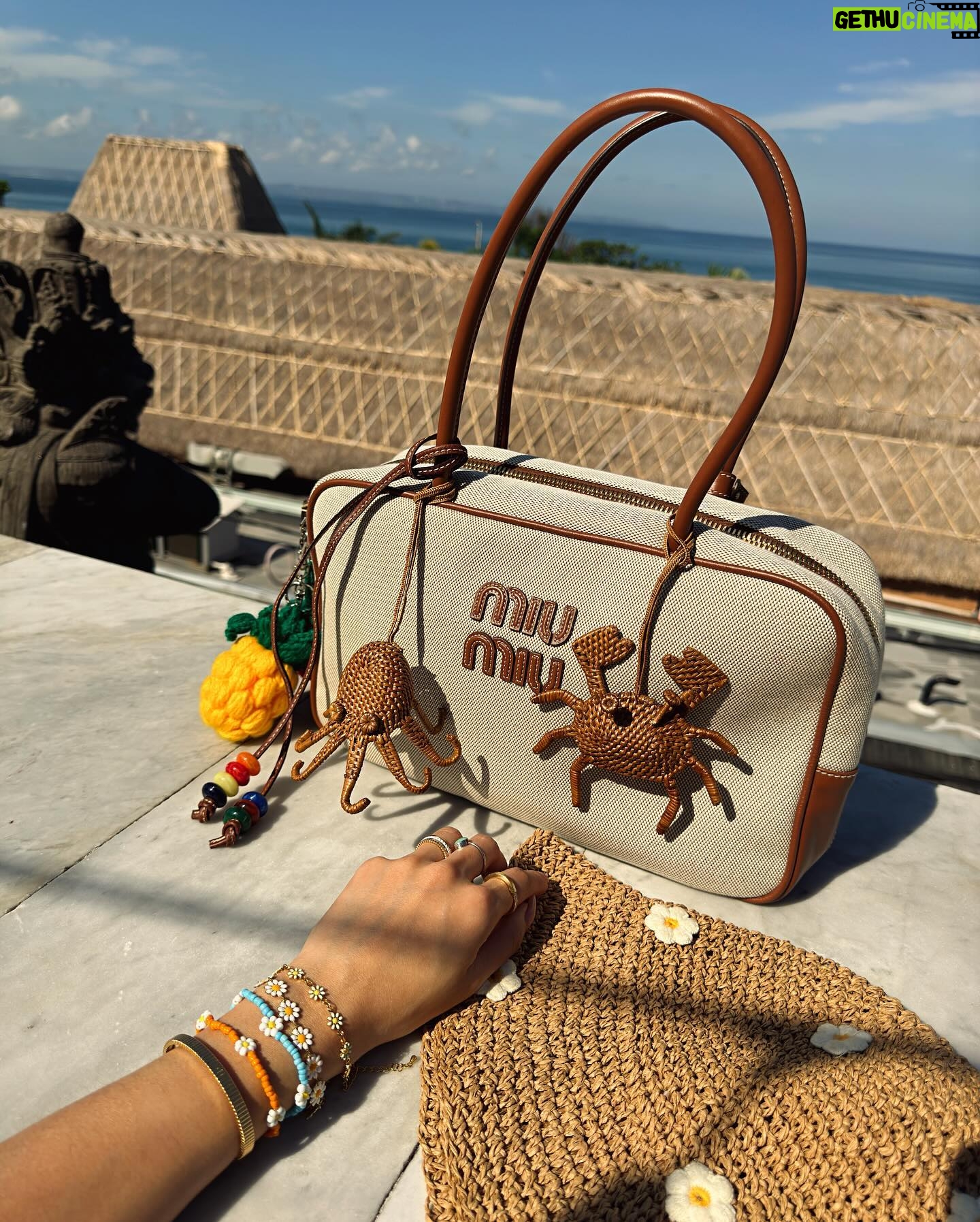 Molly Chiang Instagram - MiuMiu girl in Bali ✨💚🧡🖤 #miumiu @miumiu - 在峇里島買到的戰利品讓我心情整個變彩色起來 心情快樂到跟今天的穿搭一樣繽紛樂😂 就是我掛在包包上的螃蟹 章魚編織娃娃掛飾🥹❤️ 這個掛飾是我在 @Amankila 禮品店買到的 當時看到被這個可愛到心臟漏一拍(好浮誇) 太有趣太可愛的掛飾了!!! 而且掛在這顆MiuMiu包上面顏色有夠配耶? 毫無違和🤣 你們說是不是超可愛! 你們喜歡螃蟹還是章魚的? 另一個超愛的戰利品 就是脖子跟手上的小花項鍊跟手鍊 這個就是峇里島市集的飾品攤販買到的 大家如果去峇里島有逛一些市集 可以都看看有沒有 還有很多顏色的 我自己買了白色跟薄荷綠💚☺️ 在峇里島還是要來點色彩的搭配🥹 自己好喜歡這組照片的配色 吃早餐的時候看到這面藍色的牆壁就覺得應該很適合配我這套拍💙😍 喜歡這套嗎😙