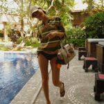 Molly Chiang Instagram - MiuMiu girl in Bali ✨💚🧡🖤 #miumiu @miumiu - 在峇里島買到的戰利品讓我心情整個變彩色起來 心情快樂到跟今天的穿搭一樣繽紛樂😂 就是我掛在包包上的螃蟹 章魚編織娃娃掛飾🥹❤️ 這個掛飾是我在 @Amankila 禮品店買到的 當時看到被這個可愛到心臟漏一拍（好浮誇） 太有趣太可愛的掛飾了！！！ 而且掛在這顆MiuMiu包上面顏色有夠配耶？ 毫無違和🤣 你們說是不是超可愛！ 你們喜歡螃蟹還是章魚的？ 另一個超愛的戰利品 就是脖子跟手上的小花項鍊跟手鍊 這個就是峇里島市集的飾品攤販買到的 大家如果去峇里島有逛一些市集 可以都看看有沒有 還有很多顏色的 我自己買了白色跟薄荷綠💚☺️ 在峇里島還是要來點色彩的搭配🥹 自己好喜歡這組照片的配色 吃早餐的時候看到這面藍色的牆壁就覺得應該很適合配我這套拍💙😍 喜歡這套嗎😙