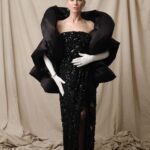 Naomi Watts Instagram - Naomi Watts’ Balenciaga look at the 2024 Met Gala.   Actress Naomi Watts attended the 2024 Met Gala in a custom Balenciaga Tablecloth Couture Dress, which was upcycled from a black lace garment embroidered with jet beads and sequins.   The bustier dress, made of a floral crochet tablecloth measuring 2.1 meters in length and 1.5 meters in diameter, was a reinterpretation of Look 63 from Summer 24.   The padded stola worn over the dress is made of black double satin, with an exaggerated filling that sculpts the overall look. For the stola, sustainability is essential, with a conscious choice to use an eco-friendly filling instead of feathers. This choice aligns with Balenciaga’s modern ethics while maintaining the gown’s timeless elegance.   Made of jet beads and sequins stacked in an irregular manner around the tablecloth’s cut-outs, the embroidery was hand-rendered by the Paris-based Atelier Montex, a venture founded in 1949 with a unique savoir-faire regarding high fashion embroideries.   The gown features lace that is delicately intertwined with sequins, jet beads, and black crystals. These all mirror the vintage tablecloth’s complex pattern. Each element contributes to a richly textured surface, and each recalls Cristóbal Balenciaga’s Spanish heritage.   Over 600 hours of meticulous embroidery brought this vision to life.   The overall styling nods to Look 135 from Cristóbal Balenciaga’s 1961 Spring/Summer collection, and it also nods to the party’s dress code: The Garden of Time.   © Atelier Montex & Le 19 M