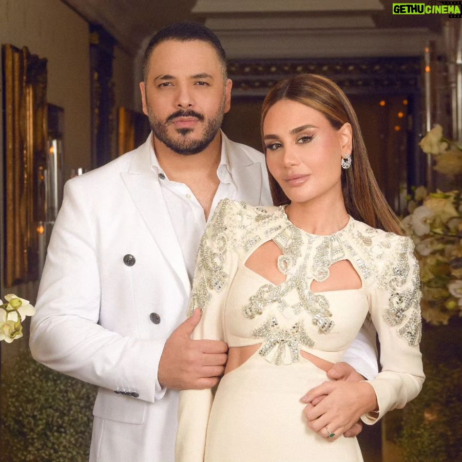Ramy Ayash - 34.6K Likes - رامي عيّاش.. يتزوج مرة ثانية !
لينك الفيديو في البايو
لم تكن الذكرى السنوية العاشرة على زواج البوب ستار "رامي عيّاش" كسواها ، هو الذي يقدم دوماً تحف فنيّة استثنائية، حضرت هذه الليلة الحالمة ليتغنى رامي بأفكاره الخلاقة ويأخذنا معه الى عالمه بمشهدية قلّما يقال عنها ملكية بلمسات راقية.
رامي الذي أراد ان يخلد هذه الذكرى السعيدة مع محبيه، فاجىء زوجته مصممة الأزياء داليدا عياش بعد عشاء متواضع وخاص مع العائلة في فندق هيلتون حبتور بمناسبة عيد ميلادها الذي حوله الى حفل زفاف أدهش به داليدا والجميع .
وتكلل الحفل اطلالة ملكية لداليدا اختارها لها مصمم الازياء العالمي زهير مراد الغالي على قلب داليدا، بفستان ابيض تناسب تماماً مع هذه الليلة الحالمة كان بانتظارها في الجناح الملكي مع فريق عمل جاهز لتغيير الماكياج مع افون ابي حاتم والشعر مع وديع شليطا وفادي عواد .
وبتنسيق مع الماركة الأحب الى رامي وداليدا روسونيرو ميشال زغيب ، اختار رامي خاتم بتصميم خاص يقال انه من أجمل تصاميم الماركة العالمية وهو الحجر واللون الاحب على قلب داليدا الاميرالد مرصع بالألماس اشبه الى الخيال.
ولدى دخولك الى الصالة المزدانة بأنامل منسق الحفلات وليد باز "باز ايفينت "، تلفتك فخامة الديكور والورود التي تحيط بك كيفما نقّلتَ نظريك.. حيث انتظرهم الأصدقاء والأحباب والعائلة ليستقبلوا العرسان، ولم يكتف رامى عياش بذلك انما خصها بأغنية من اللهجة اللبنانية وهى "يا مراية بيتى" زخرفها بألق وجده وعشقه من ألحانه وكلمات الشاعر مازن غنام وتوزيع الكسندر ميساكيان.. واختتم الحفل بسهرة فنية مميزة مع محبيه الذين رفضوا إلا ان يشاركوه فرحته.