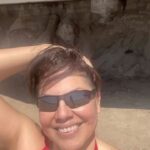 Sara Ramirez Instagram – Wishing my queer, trans, non-binary, and accomplice community a joyful and generative Pride. We are facing enraging   saddening realities and we also have each other: where we get to envisage and co-create an experience of care, love, solidarity, and joy. I’m holding space for all of our feelings and multitudes, as well as the resistance our existence continues to be. We are allowed to be imperfect, complex, messy, silly, salty, beautiful, all the rest and know our humanity matters no matter what the inaccurate projections say. We deserve to just be, today and everyday.  I love you. 
🏳️‍⚧️🏳️‍🌈💐♥️
.
.
Selfie video of Sara from the shoulders up dancing on the beach to Beyonce’s “Plastic Off the Sofa”, in a red bathing suit and black sunglasses, @trudy0nduty in a white ballcap and olive briefs, laying on a towel on the sand in the background next to a rainbow umbrella, some beach chairs and blue and white striped towels. The camera spins with a smiling Sara, the ocean waves behind them, as they play with their hair and raise their arm and hand to the sky, exhaling a revitalizing deep salty beach filled breath!