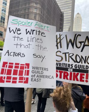 Sara Ramirez Instagram - Showing up in solidarity with @wgaeast for the Writers Guild strike and picket line in NYC. Better contracts NOW! The content we consume (and some of us perform 🙋🏽) would be NOTHING without writers. Thank you to all who are showing up to picket, pass out water, coverage, and all who are leading this action. I am here in solidarity as a member of WGA sibling union SAG/AFTRA. Power to the people! Also can I just say how many hilarious and creative picket signs there are? BECAUSE WRITERS WROTE THEM. 
.
Pic in color of 2 signs in the picket line (I’m holding the one that’s about writing the lines actors say:)) that read: “Spoiler Alert: We write the lines that the actors say. WRITERS GUILD OF AMERICA EAST”, and “#WGA STRONG, WRITERS GUILD ON STRIKE!”