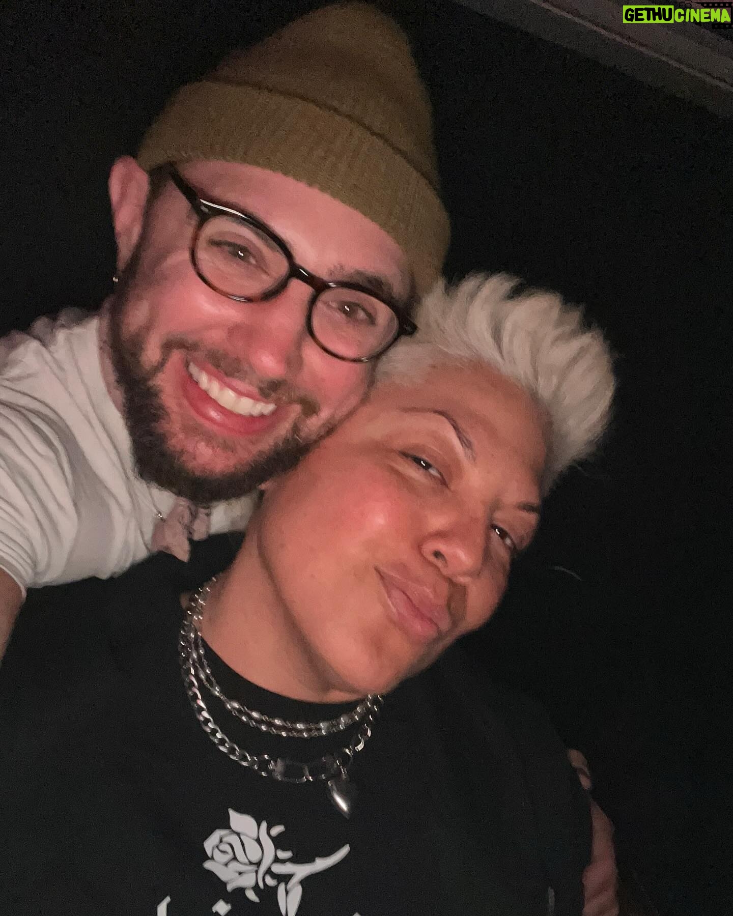 Sara Ramirez Instagram - As much space as I make for anger/rage/sadness, it is imperative that I make as much- if not more- space for joy and pleasure. I’m a human being who deserves love, joy, pleasure, silliness, fun, and for my whole self to be accepted and respected. Here is some of my joy in recent days! . . Pic 1: selfie of me squinting in the sun cosplaying Billy Idol with a curled lip, recently changed hair to platinum, laying on a towel with my sunglasses and Parable of the Sower (yes! It took me forever to read it! Yes! I struggle with staying focused when reading! :)) as I soak in the first rays of Spring. Pic 2: Mio in the midst of capturing one of his fave toys in his mouth. Pic 3: Me and Sawyer selfie, out and about having fun! He’s got cute glasses on and an olive beanie. I’m, of course, wearing black. Pic 4,5,6: beautiful blooming Spring at Brooklyn Botanical Gardens, Sawyer taking a pic, and a video of gorgeous reds blooming. Pic 7: my red nails for Red Ink at Joes Pub. I wonder why my middle finger nails are watermelon art? 🤔🍉 Pic 8,9: selfies of me and @trudy0nduty at the park loving on each other with hugs and smooches. Big bright yellow blooming behind us. Video: me being silly, making my own music, being in on all the jokes. We must have JOY to counteract and resist the systems that would rather we didn’t exist. 👋🏽🥰❤️🔥☀️🪻🌱
