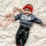 Tara Lipinski Instagram – Repping Team USA always. ❤️🤍💙
Gigi got quite the chuckle out of mom trying to get a pic with all the rolling and toe touches. @usagym should we start her early?! 

#mom #parenting #baby