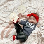 Tara Lipinski Instagram – Repping Team USA always. ❤️🤍💙
Gigi got quite the chuckle out of mom trying to get a pic with all the rolling and toe touches. @usagym should we start her early?! 

#mom #parenting #baby