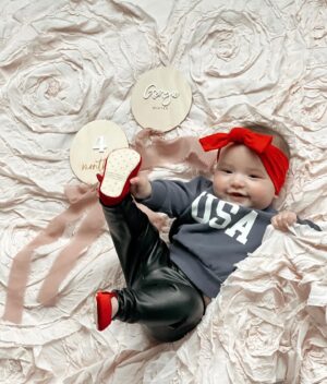 Tara Lipinski Instagram - Repping Team USA always. ❤️🤍💙
Gigi got quite the chuckle out of mom trying to get a pic with all the rolling and toe touches. @usagym should we start her early?! 

#mom #parenting #baby