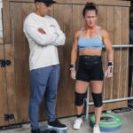 Tia-Clair Toomey Instagram – Sunday, 1:34pm: The fact that there is now a whole competition floor on the Dell Diamond concourse where a concession stand used to be — complete with 5 sets of double-under and lifting platforms, barricades and a sharp-looking @roguefitness backdrop — feels so natural, it’s easy to assume this was always the plan. It was not, but after four days of Book of Job-like weather, @caityhenniger and @billhenniger are taking no chances for the final event. 

Moving “The Cleanup” from the field to the concourse at the last minute is the latest example of the kind of logistical sorcery the @RogueInvitational has been performing behind the scenes all weekend. But not even Rogue can change the temperature, which dropped from 75° to 50° in the span of an hour earlier this morning. The top heat of women, the last of four heats, spend most of their 45 minute wait trying to stay warm; when @alexgazan_ 🇺🇸 takes a chair into the women’s bathroom, @laurahorvaht 🇭🇺 and @gabimiga 🇵🇱 follow suit. 

@tiaclair1 🇦🇺 remains outside, pacing around the warmup area with @shaneorr01’s jacket draped across her shoulders like a cape, superhero style. Shane, down to a just a longsleeve t-shirt, paces with her, shivering so hard he’s practically vibrating. A member of the Rogue event team notices, removes his own brand new Invitational hoodie and offers it to Shane, who accepts it with a mix of surprise and gratitude. By the time he pulls it on, @nick.p.jeffries is back at work, the only person on the concourse wearing shorts and a t-shirt.

If you want to know what people mean when they say the Rogue Invitational goes above and beyond — it’s this.

✍🏽: @christinedca
📷: @emomphoto