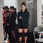 Tia-Clair Toomey Instagram – Sunday, 1:34pm: The fact that there is now a whole competition floor on the Dell Diamond concourse where a concession stand used to be — complete with 5 sets of double-under and lifting platforms, barricades and a sharp-looking @roguefitness backdrop — feels so natural, it’s easy to assume this was always the plan. It was not, but after four days of Book of Job-like weather, @caityhenniger and @billhenniger are taking no chances for the final event. 

Moving “The Cleanup” from the field to the concourse at the last minute is the latest example of the kind of logistical sorcery the @RogueInvitational has been performing behind the scenes all weekend. But not even Rogue can change the temperature, which dropped from 75° to 50° in the span of an hour earlier this morning. The top heat of women, the last of four heats, spend most of their 45 minute wait trying to stay warm; when @alexgazan_ 🇺🇸 takes a chair into the women’s bathroom, @laurahorvaht 🇭🇺 and @gabimiga 🇵🇱 follow suit. 

@tiaclair1 🇦🇺 remains outside, pacing around the warmup area with @shaneorr01’s jacket draped across her shoulders like a cape, superhero style. Shane, down to a just a longsleeve t-shirt, paces with her, shivering so hard he’s practically vibrating. A member of the Rogue event team notices, removes his own brand new Invitational hoodie and offers it to Shane, who accepts it with a mix of surprise and gratitude. By the time he pulls it on, @nick.p.jeffries is back at work, the only person on the concourse wearing shorts and a t-shirt.

If you want to know what people mean when they say the Rogue Invitational goes above and beyond — it’s this.

✍🏽: @christinedca
📷: @emomphoto
