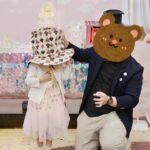 Anjaylia Chan Instagram – @babyhosanna is  5️⃣🎉
(文長慎入。最後有一些party 小tips 喔） 

本來除了替代滿月酒和百日宴的一歲生日會外，黃小姐們的生日都應該是待在家裏簡單過的。沒想到參加朋友們的生日會多了之後，這小姐也希望可以開個邀請很多朋友的生日party 了。於是呢，黃小姐就直接繞過難纏的媽媽，跟爸爸說：「爸爸，我5歲可唔可以開大生日party呀？如果唔得都唔緊要嘅，我會明白，我會乖㗎。」。 

結果呢？想都不用想吧！深受女兒乖巧懂事而感動的黃先生不但say yes，更是即場豪言立下了黃家小孩逢5跟0字尾就舉辦大型生日party 的傳統… （爸爸一言既出，本人除了 😧、🫨、🙄、🫠之外還能有甚麼反應呢？）

派對主題不要公主，也不要任何熱門卡通，就要從嬰兒時開始一直伴在身邊的小熊 (小熊叫臍臍)主題 …沒現成的，叫我怎麼辦呢？🫠 幸運的是有一個派對能手auntie @sannietang ，二話不說幫我們設計和訂backdrop；我們家很愛的蛋糕好手 @patisserieshania 幫忙量身定製超好吃的小熊日式士多啤梨輕芝士蛋糕 （再一次，在現場不斷被問可不可以添吃），還有 @balloon_hk 設計的小熊生日氣球。

一知道可以辦臍臍party ，Hosanna 在家裏竟馬上飛奔撲向臍臍問：「乖乖！你開唔開心呀？」。 喂！主角錯了吧？我是想要你開心的好嗎？！

然後便是構思回禮小包、請魔術師、攝影師、張羅食物等等了…
(怎麼我很有一種辦婚禮的勞累感…🫠） 

沒想到最難的是草擬賓客名單…這比我當年婚禮還難好嗎？！
除了教會一直長大的小朋友、契爸爸媽媽們的小孩、還有學校的朋友、同學…有一些小朋友還有兄弟姊妹的説。要是按她要求全請來是要book 會展嗎？！最後……只好做出殘忍的舉動—— 抽籤。順便來上一上舉手不回沒得反悔的課🫣 

Anyways，還是很感恩這個寶貝可以健康快樂的成長。
看着本來是一團糯米般的寶寶眨眼長成一個超過110cm 的小女生，覺得時間真的也過太快…面對考小學的關口，我也不奢望你成龍成鳳，只要能愉快平安的成長、過渡就好了( 當然，這也是我要祝福自己的🥹）。
但願你能走在天父爸爸的翅膀蔭下，一生平安健康、幸福快樂。

謝謝大家對 @babyhosanna 的疼愛💖

Party tips : 
1） 只要是八歲以下的生日派對，一定要請魔術師！！！一個人幫你扭波波、表演魔術、主持小遊戲、主持敲糖果盒、切蛋糕，全包！全場八歲以下小孩都被吸引乖乖坐定兩個小時不亂跑。爸媽們就可以鬆口氣喝一杯了！親愛的魔術師先生，請收下我的敬佩的膝蓋。🧎‍♀️

2）八歲以下還是很喜歡充氣滑梯的，起初還以為會太悶太baby，沒想到大受歡迎。

3）經歷40多位小朋友臨床實證，最受歡迎的生日派對食物如下:
1.新鮮生果 (士多啤梨、提子、藍莓）、2. 七彩啫喱糖 、3.雞翼

4） 薯片最受大人歡迎，建議可買很多包迷你包裝的，一人一包拿着周圍走，不用一包大的你拿兩塊，我又拿兩塊…

5） 大人細路原來都很喜歡玩紋身貼紙。一張細枱、一堆紋身貼紙、一碗水、幾塊海綿。搞掂🤝

特別鳴謝:
攝影師 @zenowtl 
偉大的CO搞手: 契媽媽爸爸、契BB @rach_bu @johnnykstam @nicholasbabytam t

Helpers @evelynchoii 、表哥、uncle tai 

結論：攰過結婚。但主角同來賓開心就好。我唞唞先。🥹