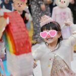 Anjaylia Chan Instagram – @babyhosanna is  5️⃣🎉
(文長慎入。最後有一些party 小tips 喔） 

本來除了替代滿月酒和百日宴的一歲生日會外，黃小姐們的生日都應該是待在家裏簡單過的。沒想到參加朋友們的生日會多了之後，這小姐也希望可以開個邀請很多朋友的生日party 了。於是呢，黃小姐就直接繞過難纏的媽媽，跟爸爸說：「爸爸，我5歲可唔可以開大生日party呀？如果唔得都唔緊要嘅，我會明白，我會乖㗎。」。 

結果呢？想都不用想吧！深受女兒乖巧懂事而感動的黃先生不但say yes，更是即場豪言立下了黃家小孩逢5跟0字尾就舉辦大型生日party 的傳統… （爸爸一言既出，本人除了 😧、🫨、🙄、🫠之外還能有甚麼反應呢？）

派對主題不要公主，也不要任何熱門卡通，就要從嬰兒時開始一直伴在身邊的小熊 (小熊叫臍臍)主題 …沒現成的，叫我怎麼辦呢？🫠 幸運的是有一個派對能手auntie @sannietang ，二話不說幫我們設計和訂backdrop；我們家很愛的蛋糕好手 @patisserieshania 幫忙量身定製超好吃的小熊日式士多啤梨輕芝士蛋糕 （再一次，在現場不斷被問可不可以添吃），還有 @balloon_hk 設計的小熊生日氣球。

一知道可以辦臍臍party ，Hosanna 在家裏竟馬上飛奔撲向臍臍問：「乖乖！你開唔開心呀？」。 喂！主角錯了吧？我是想要你開心的好嗎？！

然後便是構思回禮小包、請魔術師、攝影師、張羅食物等等了…
(怎麼我很有一種辦婚禮的勞累感…🫠） 

沒想到最難的是草擬賓客名單…這比我當年婚禮還難好嗎？！
除了教會一直長大的小朋友、契爸爸媽媽們的小孩、還有學校的朋友、同學…有一些小朋友還有兄弟姊妹的説。要是按她要求全請來是要book 會展嗎？！最後……只好做出殘忍的舉動—— 抽籤。順便來上一上舉手不回沒得反悔的課🫣 

Anyways，還是很感恩這個寶貝可以健康快樂的成長。
看着本來是一團糯米般的寶寶眨眼長成一個超過110cm 的小女生，覺得時間真的也過太快…面對考小學的關口，我也不奢望你成龍成鳳，只要能愉快平安的成長、過渡就好了( 當然，這也是我要祝福自己的🥹）。
但願你能走在天父爸爸的翅膀蔭下，一生平安健康、幸福快樂。

謝謝大家對 @babyhosanna 的疼愛💖

Party tips : 
1） 只要是八歲以下的生日派對，一定要請魔術師！！！一個人幫你扭波波、表演魔術、主持小遊戲、主持敲糖果盒、切蛋糕，全包！全場八歲以下小孩都被吸引乖乖坐定兩個小時不亂跑。爸媽們就可以鬆口氣喝一杯了！親愛的魔術師先生，請收下我的敬佩的膝蓋。🧎‍♀️

2）八歲以下還是很喜歡充氣滑梯的，起初還以為會太悶太baby，沒想到大受歡迎。

3）經歷40多位小朋友臨床實證，最受歡迎的生日派對食物如下:
1.新鮮生果 (士多啤梨、提子、藍莓）、2. 七彩啫喱糖 、3.雞翼

4） 薯片最受大人歡迎，建議可買很多包迷你包裝的，一人一包拿着周圍走，不用一包大的你拿兩塊，我又拿兩塊…

5） 大人細路原來都很喜歡玩紋身貼紙。一張細枱、一堆紋身貼紙、一碗水、幾塊海綿。搞掂🤝

特別鳴謝:
攝影師 @zenowtl 
偉大的CO搞手: 契媽媽爸爸、契BB @rach_bu @johnnykstam @nicholasbabytam t

Helpers @evelynchoii 、表哥、uncle tai 

結論：攰過結婚。但主角同來賓開心就好。我唞唞先。🥹