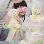 Anjaylia Chan Instagram – @babyhosanna is  5️⃣🎉
(文長慎入。最後有一些party 小tips 喔） 

本來除了替代滿月酒和百日宴的一歲生日會外，黃小姐們的生日都應該是待在家裏簡單過的。沒想到參加朋友們的生日會多了之後，這小姐也希望可以開個邀請很多朋友的生日party 了。於是呢，黃小姐就直接繞過難纏的媽媽，跟爸爸說：「爸爸，我5歲可唔可以開大生日party呀？如果唔得都唔緊要嘅，我會明白，我會乖㗎。」。 

結果呢？想都不用想吧！深受女兒乖巧懂事而感動的黃先生不但say yes，更是即場豪言立下了黃家小孩逢5跟0字尾就舉辦大型生日party 的傳統… （爸爸一言既出，本人除了 😧、🫨、🙄、🫠之外還能有甚麼反應呢？）

派對主題不要公主，也不要任何熱門卡通，就要從嬰兒時開始一直伴在身邊的小熊 (小熊叫臍臍)主題 …沒現成的，叫我怎麼辦呢？🫠 幸運的是有一個派對能手auntie @sannietang ，二話不說幫我們設計和訂backdrop；我們家很愛的蛋糕好手 @patisserieshania 幫忙量身定製超好吃的小熊日式士多啤梨輕芝士蛋糕 （再一次，在現場不斷被問可不可以添吃），還有 @balloon_hk 設計的小熊生日氣球。

一知道可以辦臍臍party ，Hosanna 在家裏竟馬上飛奔撲向臍臍問：「乖乖！你開唔開心呀？」。 喂！主角錯了吧？我是想要你開心的好嗎？！

然後便是構思回禮小包、請魔術師、攝影師、張羅食物等等了…
(怎麼我很有一種辦婚禮的勞累感…🫠） 

沒想到最難的是草擬賓客名單…這比我當年婚禮還難好嗎？！
除了教會一直長大的小朋友、契爸爸媽媽們的小孩、還有學校的朋友、同學…有一些小朋友還有兄弟姊妹的説。要是按她要求全請來是要book 會展嗎？！最後……只好做出殘忍的舉動—— 抽籤。順便來上一上舉手不回沒得反悔的課🫣 

Anyways，還是很感恩這個寶貝可以健康快樂的成長。
看着本來是一團糯米般的寶寶眨眼長成一個超過110cm 的小女生，覺得時間真的也過太快…面對考小學的關口，我也不奢望你成龍成鳳，只要能愉快平安的成長、過渡就好了( 當然，這也是我要祝福自己的🥹）。
但願你能走在天父爸爸的翅膀蔭下，一生平安健康、幸福快樂。

謝謝大家對 @babyhosanna 的疼愛💖

Party tips : 
1） 只要是八歲以下的生日派對，一定要請魔術師！！！一個人幫你扭波波、表演魔術、主持小遊戲、主持敲糖果盒、切蛋糕，全包！全場八歲以下小孩都被吸引乖乖坐定兩個小時不亂跑。爸媽們就可以鬆口氣喝一杯了！親愛的魔術師先生，請收下我的敬佩的膝蓋。🧎‍♀️

2）八歲以下還是很喜歡充氣滑梯的，起初還以為會太悶太baby，沒想到大受歡迎。

3）經歷40多位小朋友臨床實證，最受歡迎的生日派對食物如下:
1.新鮮生果 (士多啤梨、提子、藍莓）、2. 七彩啫喱糖 、3.雞翼

4） 薯片最受大人歡迎，建議可買很多包迷你包裝的，一人一包拿着周圍走，不用一包大的你拿兩塊，我又拿兩塊…

5） 大人細路原來都很喜歡玩紋身貼紙。一張細枱、一堆紋身貼紙、一碗水、幾塊海綿。搞掂🤝

特別鳴謝:
攝影師 @zenowtl 
偉大的CO搞手: 契媽媽爸爸、契BB @rach_bu @johnnykstam @nicholasbabytam t

Helpers @evelynchoii 、表哥、uncle tai 

結論：攰過結婚。但主角同來賓開心就好。我唞唞先。🥹